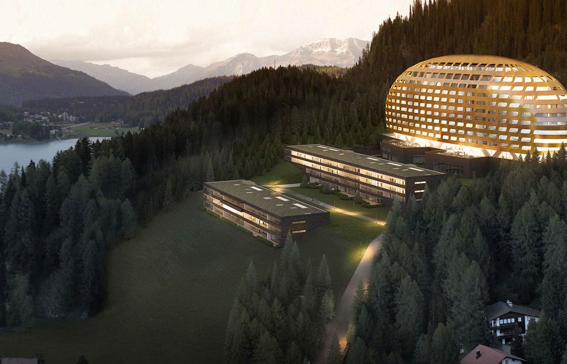 The InterContinental hotel Davos in Switzerland lit up at night in front of a scenic mountain range